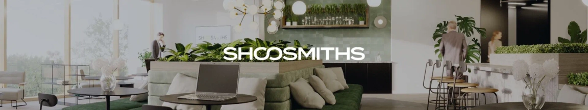 Modern office interior with comfortable seating, plants, and a laptop on a coffee table, showcasing the Shoosmiths brand.