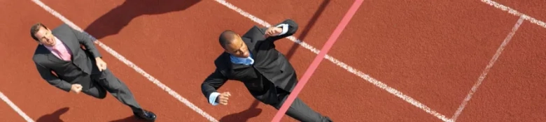 Three businessmen in suits racing on a track, symbolizing competition for investment banking jobs.