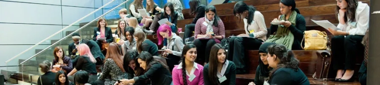 Group of people in business attire seated on steps, networking at a careers event.