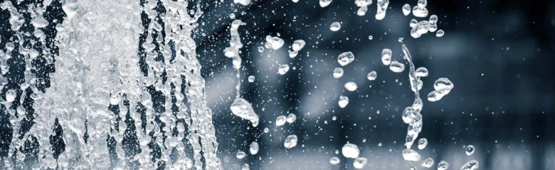 Close-up of water splashing with droplets suspended in the air, symbolizing water conservation.