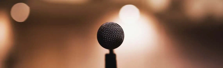 The head of a microphone. There is a blurred light in the background.