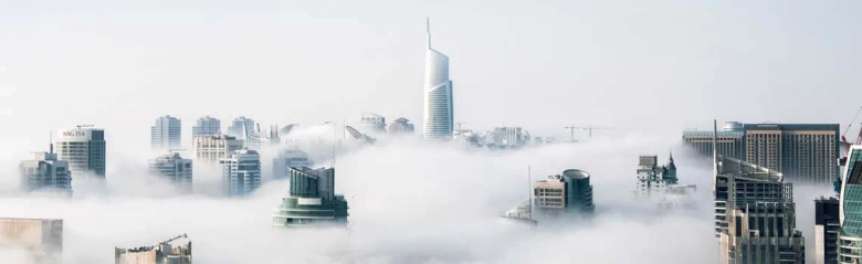A Skyscraper and other tall buildings appearing above the clouds.