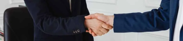 Two men in dark business suits shaking hands 