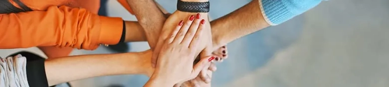 Diverse group of people stacking hands together in a gesture of teamwork and support