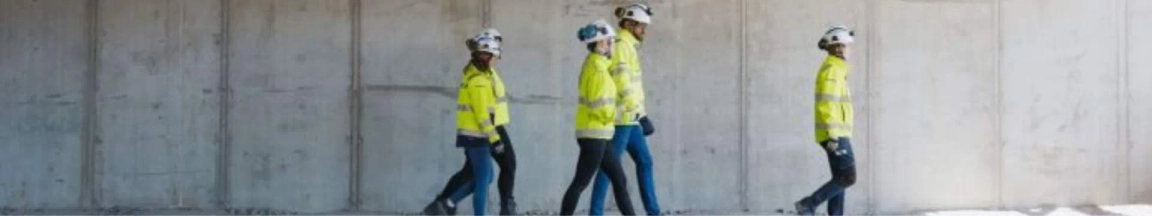 A group of people in high vis jackets walking through a building site 