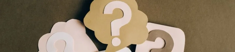  A pale question mark printed on a brown board.