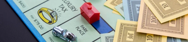 Monopoly board game elements with a red hotel piece, money, and a silver car token on the Park Place property space.