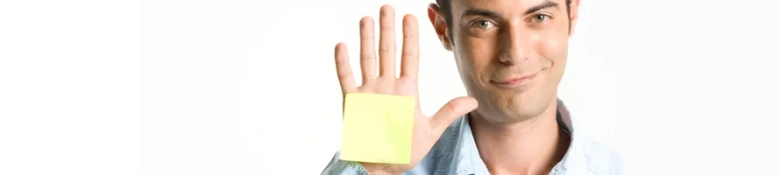 Man smiling and showing a yellow sticky note on his palm.