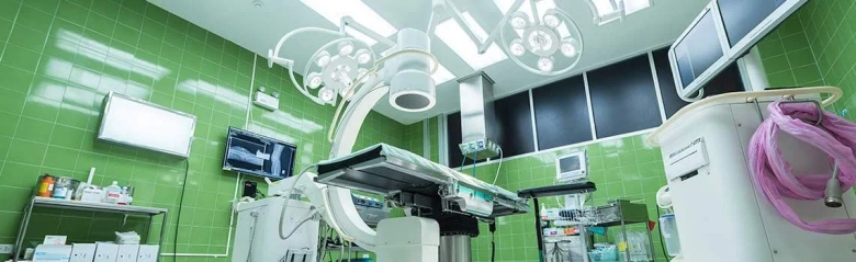 Modern hospital operating room with medical equipment and green tiles.