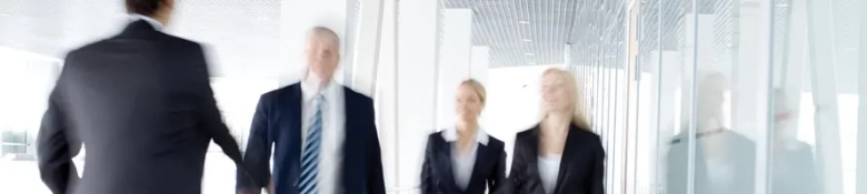 Blurred image of professionals in business attire walking in a modern office environment