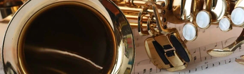 Close-up of a saxophone on sheet music, symbolizing music therapy.