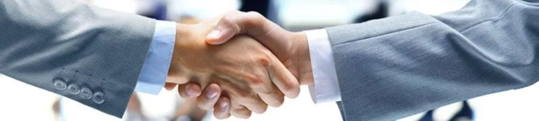 Two professionals in business attire shaking hands.