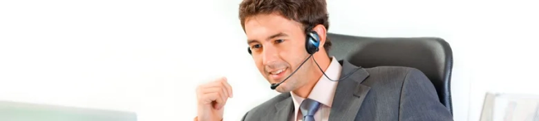 Smiling recruitment consultant wearing a headset and making a fist pump gesture at his desk.