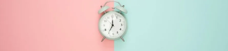  A clock against a pink and teal background. 