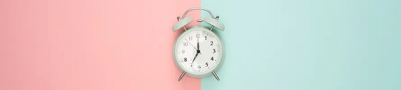 A clock against a split-pink-and-blue background