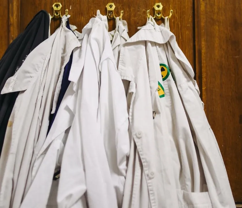 White lab coats hanging on a door.