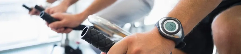 Close-up of a person's arm wearing a fitness tracker while exercising on a stationary bike.