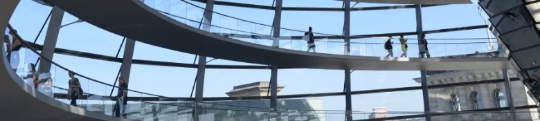 German employees walking in an a large, modern office building. 