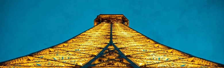 Illuminated Eiffel Tower at dusk showcasing its intricate metalwork.