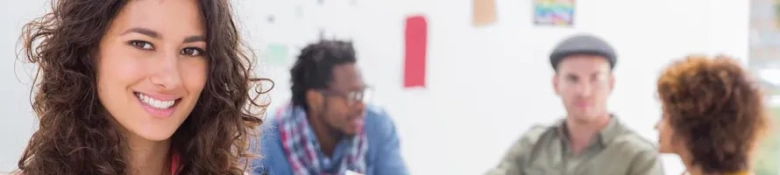 Smiling woman in foreground with a group of diverse people in discussion in the background.