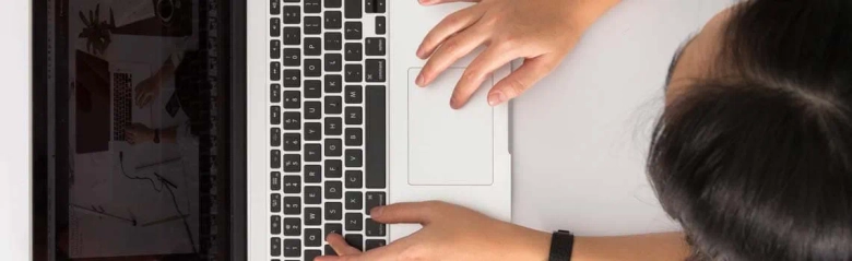 Overhead view of a person working on a laptop, typing on the keyboard.