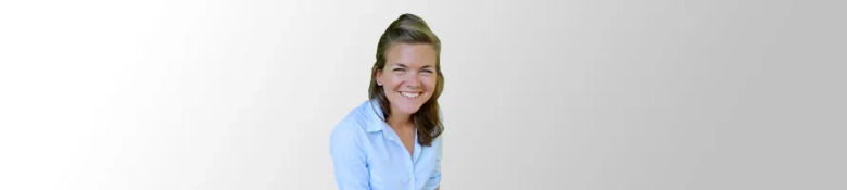 Smiling woman in a blue shirt against a light background.