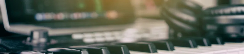 Close-up of a music production setup with a keyboard and computer monitors, suggesting a creative workspace in the music industry.