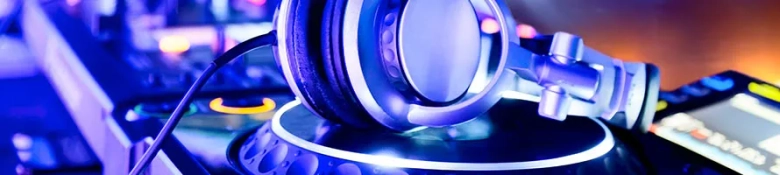 Headphones resting on a DJ mixer under blue ambient lighting.