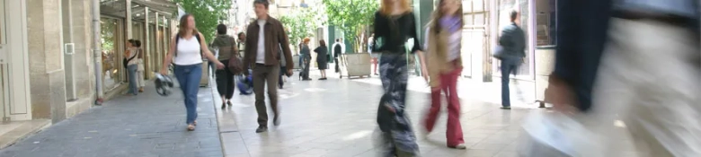 Blurred image of shoppers walking on a busy city street, conveying the hustle of retail environments.