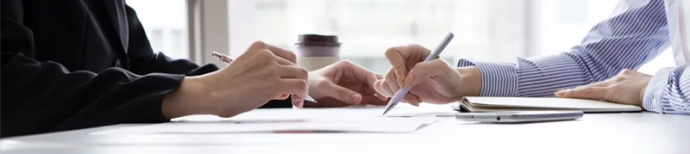 Two business women writing notes on a page during meeting