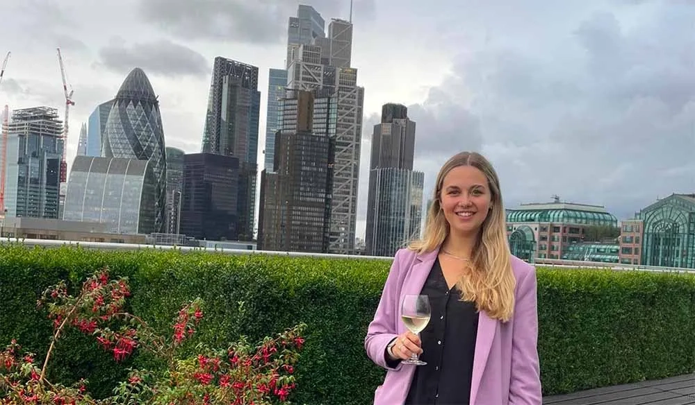 Jemma Richards, an associate at Standard Chartered, standing against a City backdrop with a glass of white wine.