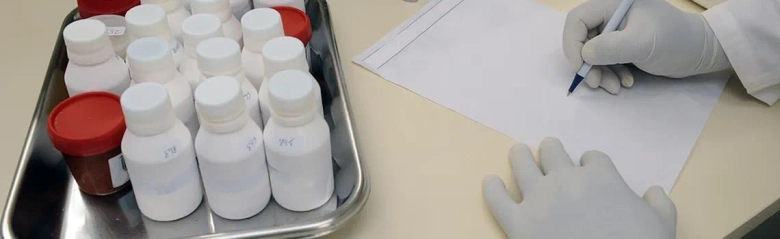 A laboratory technician writing notes on a piece of paper. 