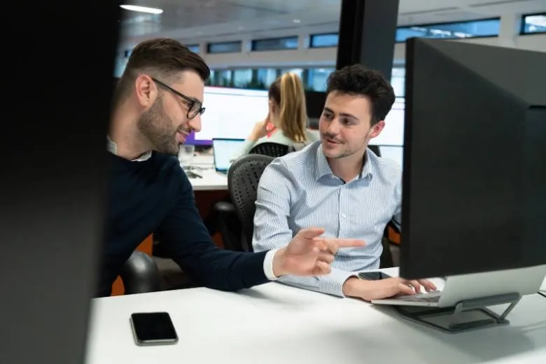 Two men talking at their desk