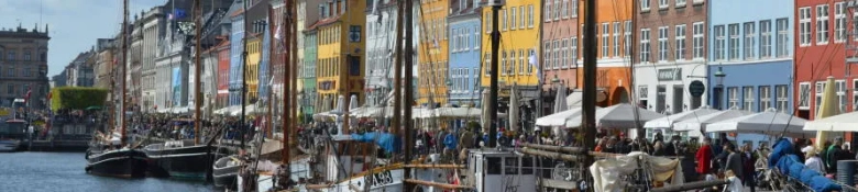 Boats in the water in front of colourful buildings in Copenhagen, Denmark. 