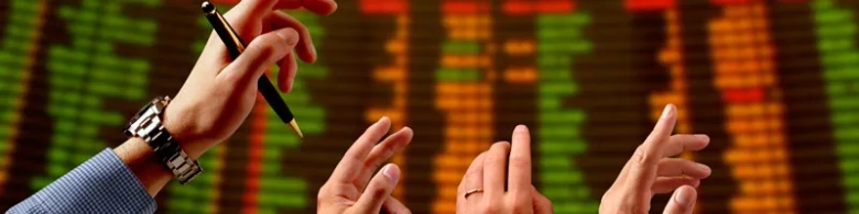 Hands of business professionals with pen over stock market data display.