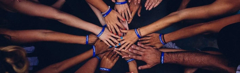 A team of charity fundraisers putting their hands together signalling that they're a team. 