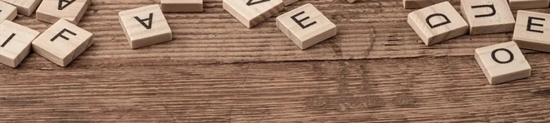 A random mixture of Scrabble pieces on a wooden table. 