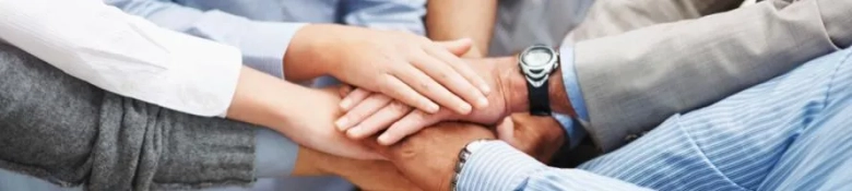 The picture shows a group of people who have piled hands together signifying teamwork. 