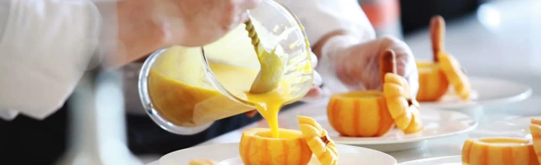 Person pouring orange juice at breakfast bar