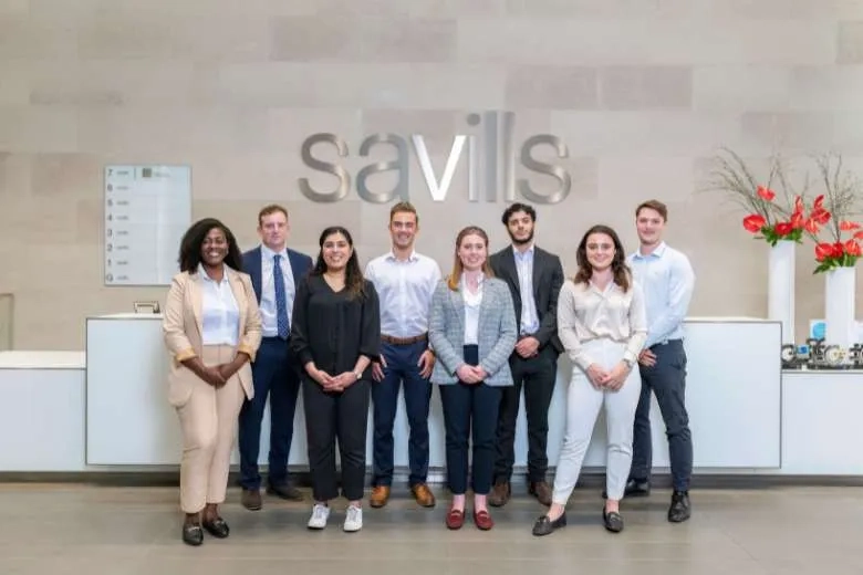 Savills employees in front of the savills sign 