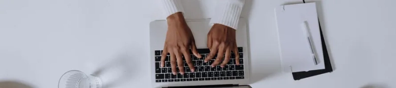 A top-down view of someone typing on a MacBook laptop.