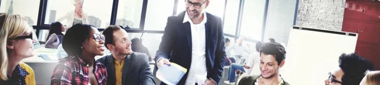 Diverse group of professionals engaged in a discussion with a smiling man leading the meeting in a bright office setting.