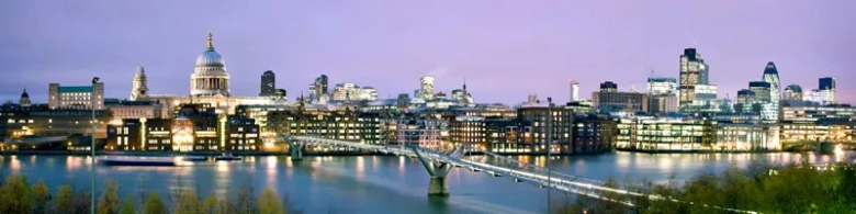 Panoramic view of London skyline at dusk with St. Paul's Cathedral and Millennium Bridge over the River Thames.
