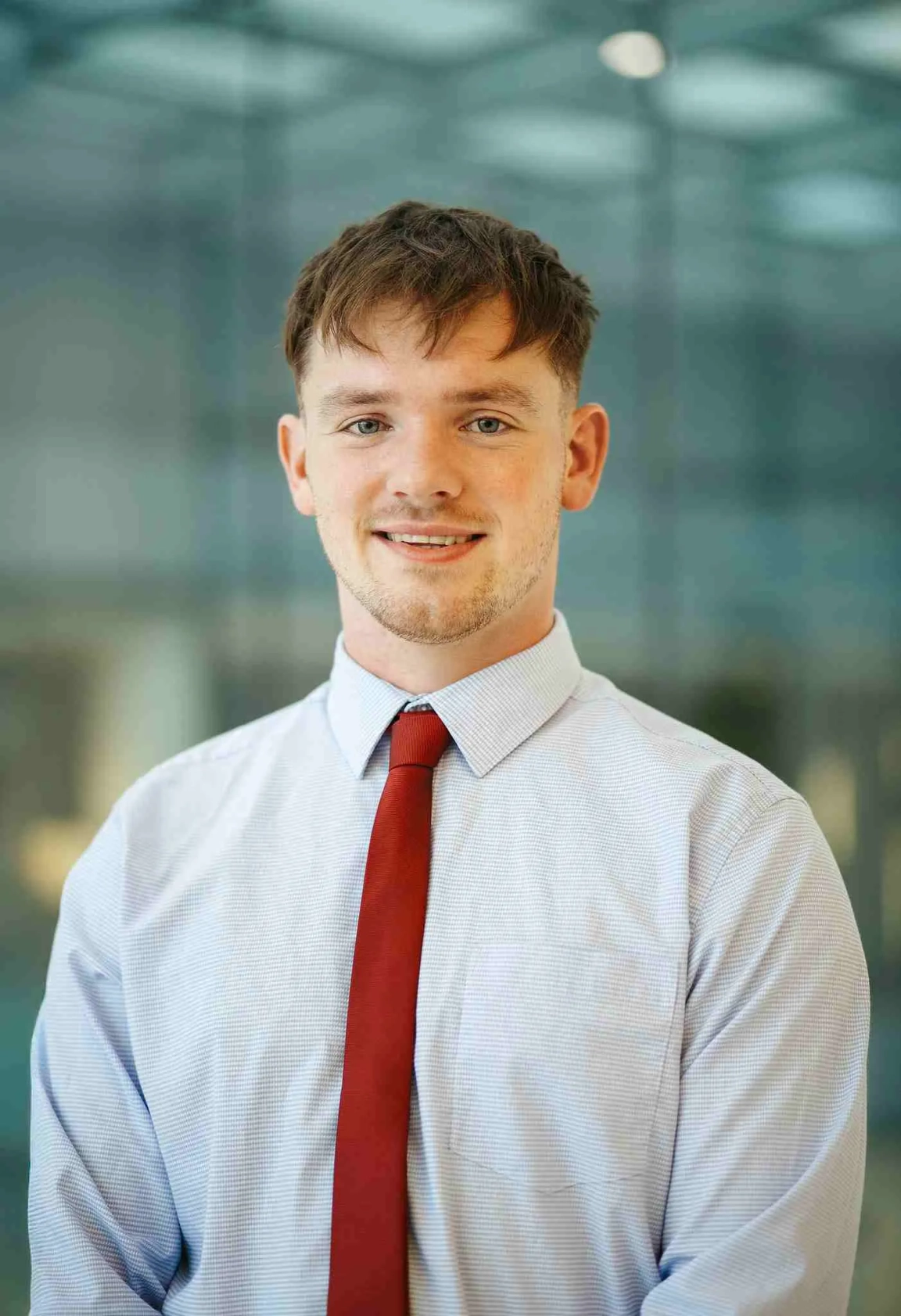 Male student with brown hair wearing a shirt and red tie