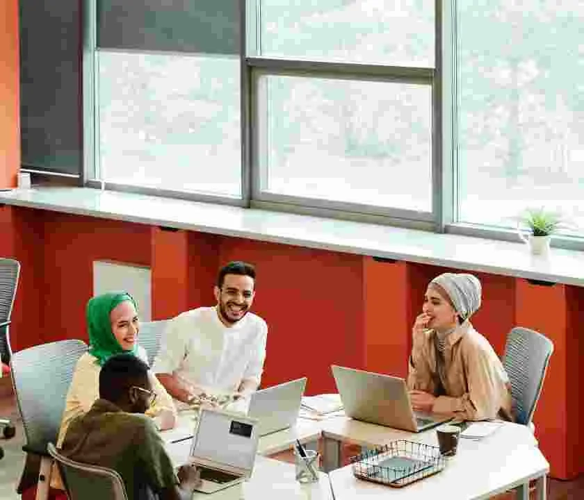 A selection of interns gathered around a business table with laptops