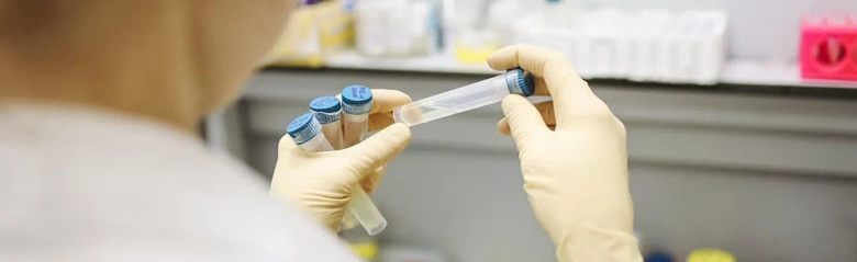 A biomedical scientist holding a sample in a test tube.