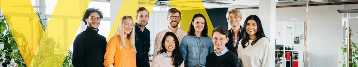 Group of diverse smiling employees standing in a modern office environment with Aviva's branding colors in the background.