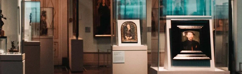 Artifacts and paintings on display in a museum gallery with descriptive placards.