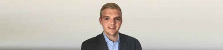 Confident young man in business attire with a neutral background.