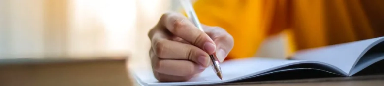 Someone using a pen to write in a book.